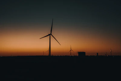 Energy sector infrastructure with wind turbines and solar panels at sunset.