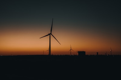 A wind farm with turbines turning against a sunset sky, symbolizing renewable energy.
