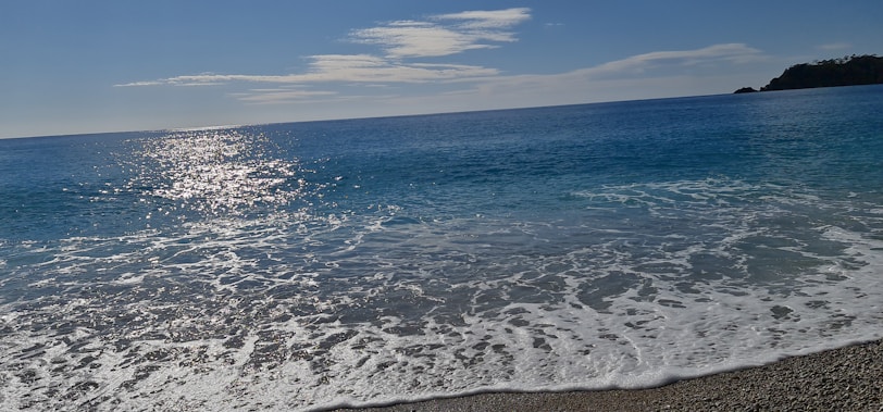 Sunlight sparkling on the clear, gentle waves of the ocean at Balgownie beach.