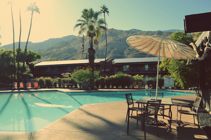 a pool with chairs and umbrellas by it