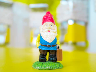 A whimsical gnome dressed with miniature artist tools like paintbrushes and palette.