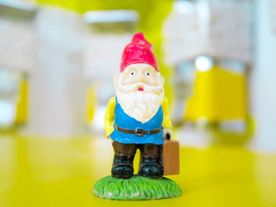 A whimsical gnome dressed with miniature artist tools like paintbrushes and palette.