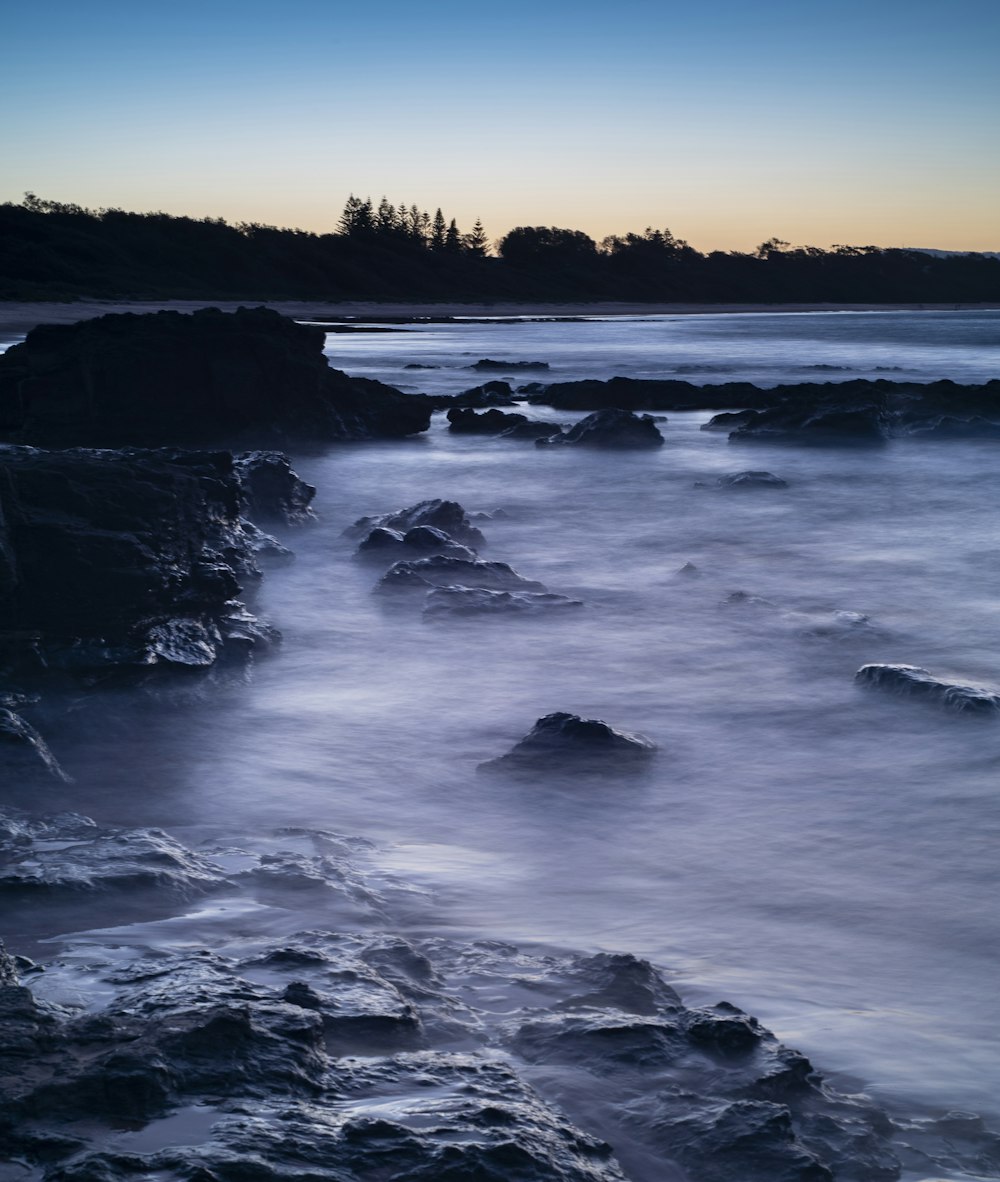 a body of water with rocks and trees in the background