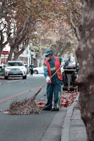 Seasonal cleanup scene with workers clearing leaves and debris from a commercial property.