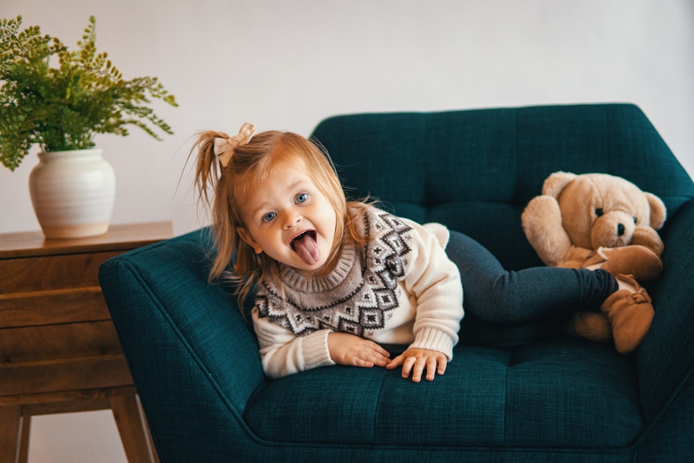 a girl sitting on a couch with a stuffed animal