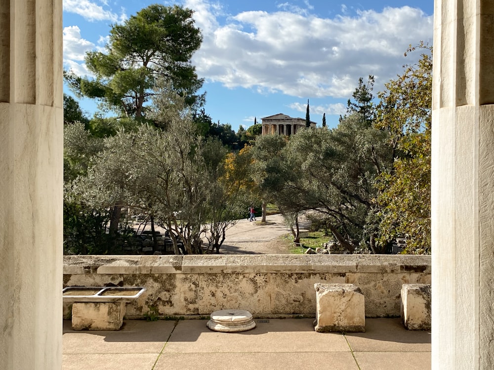 a stone wall with a bench and trees in the background