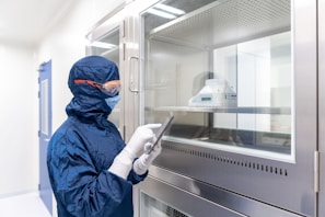 a person in a blue mask and gloves holding a tablet