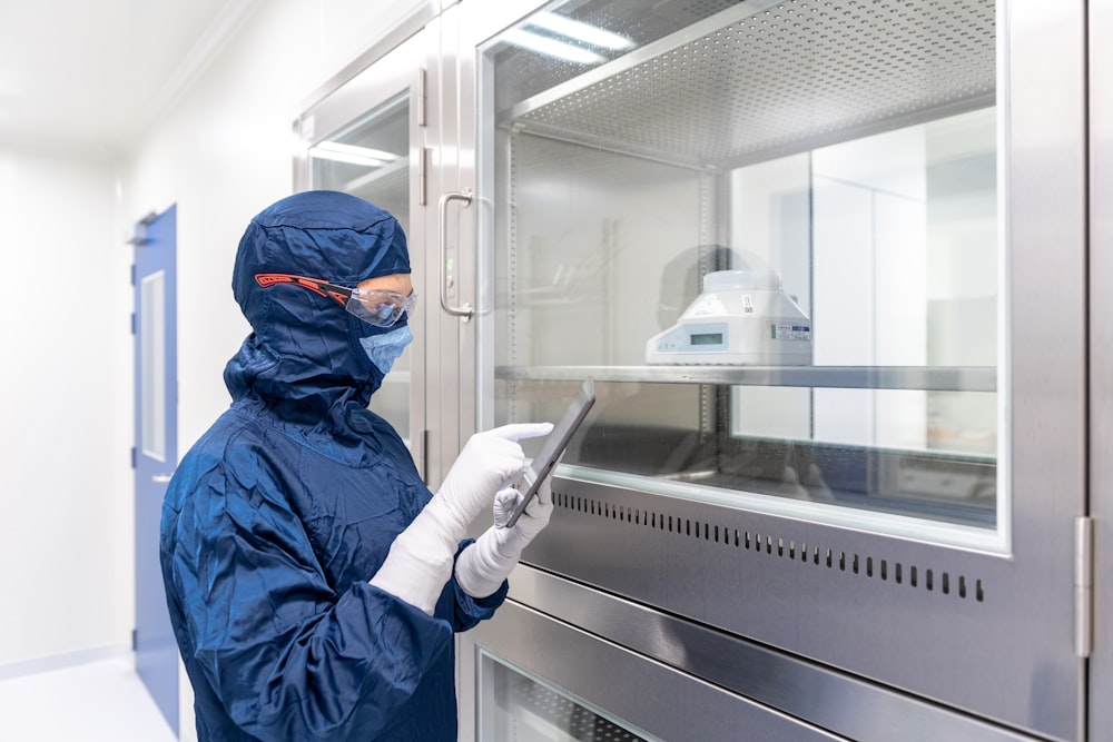 a person in a blue mask and gloves holding a tablet