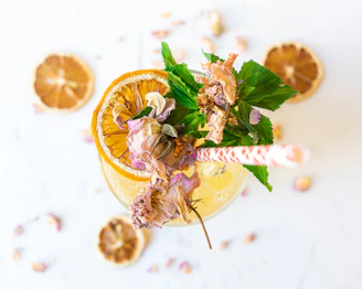 vaso de mixología con una rodaja de naranja y flores