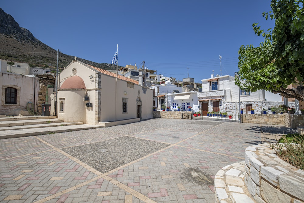 a stone paved area with buildings and a hill in the background