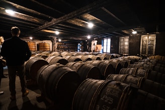 a person standing next to a stack of barrels