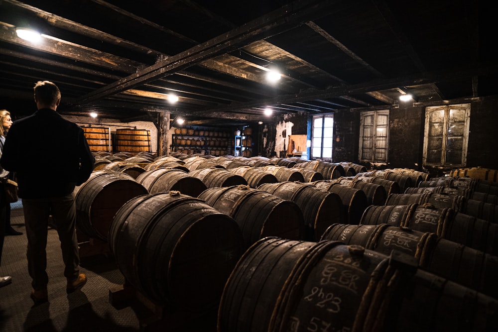 a person standing next to a stack of barrels