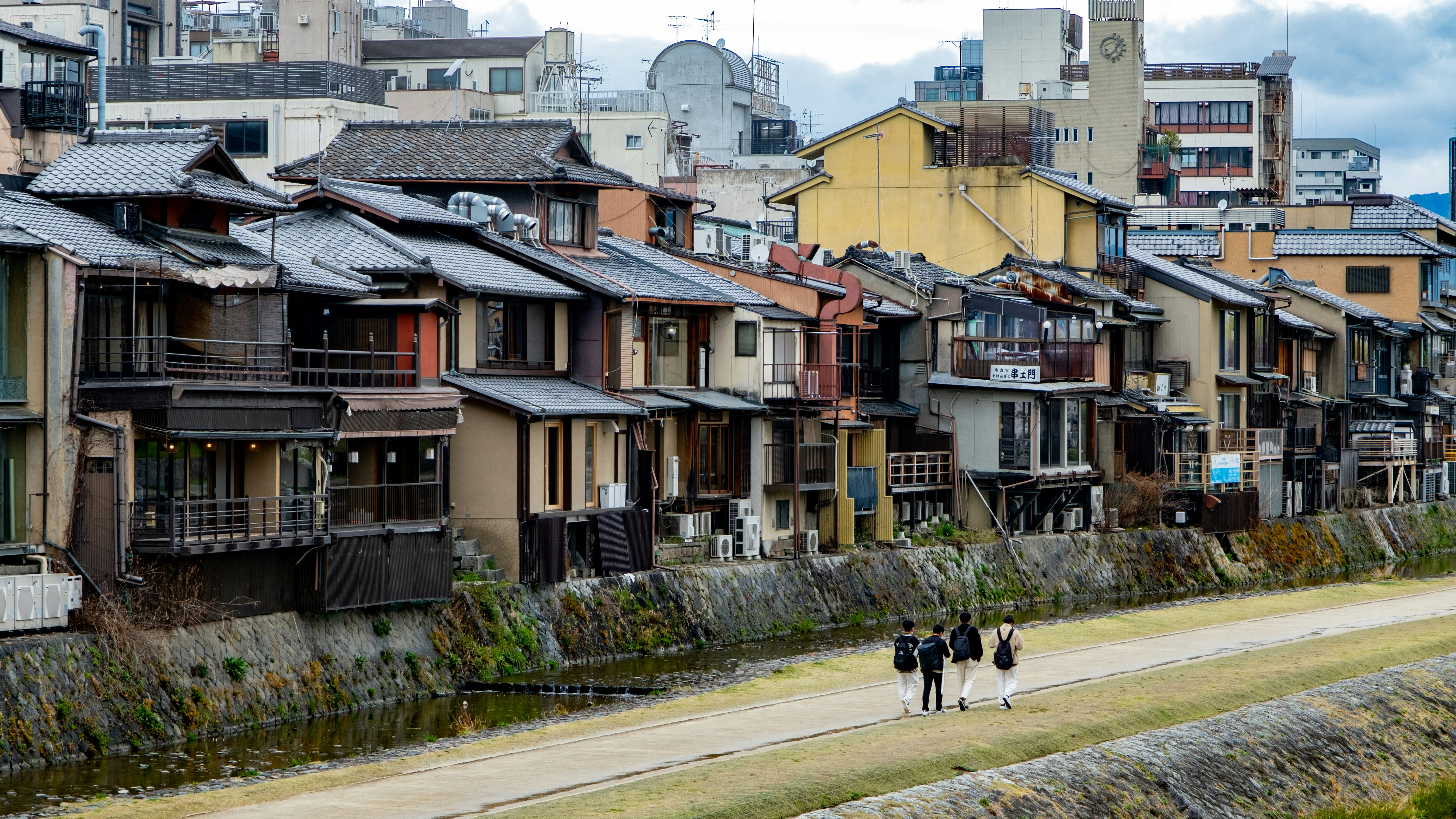 a group of people walking on a street between rows of houses