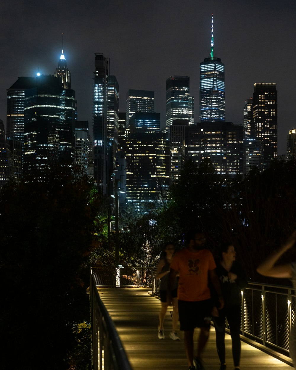 a group of people walking on a bridge with a city in the background