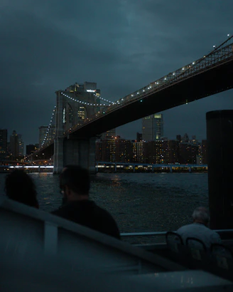 a group of people sitting on a boat looking at a bridge