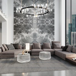 A contemporary living room showcasing a geometric chandelier, a low-profile sofa with patterned cushions, and a wooden coffee table with ceramic accents.