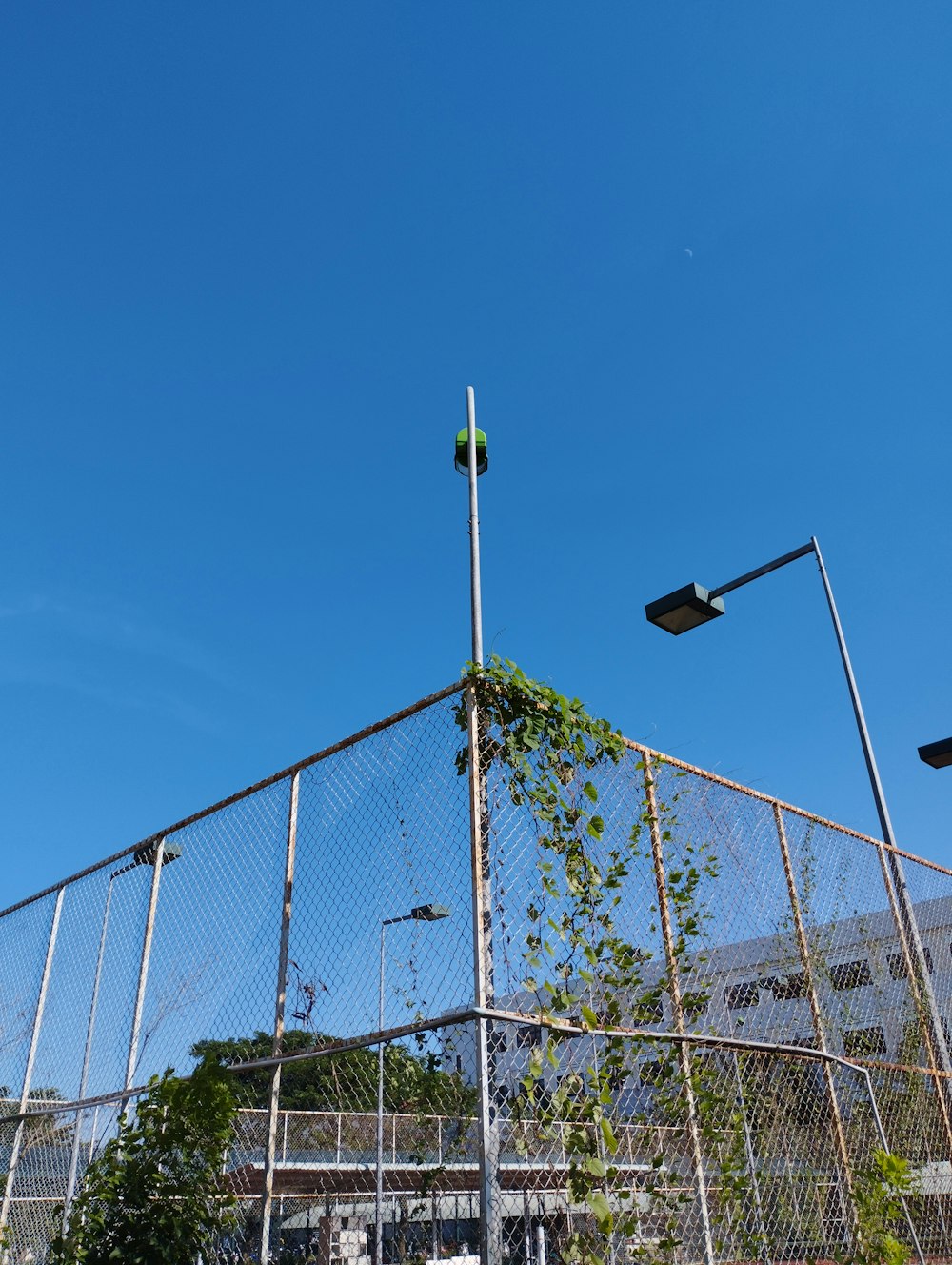 a metal fence with a metal pole and a building in the background