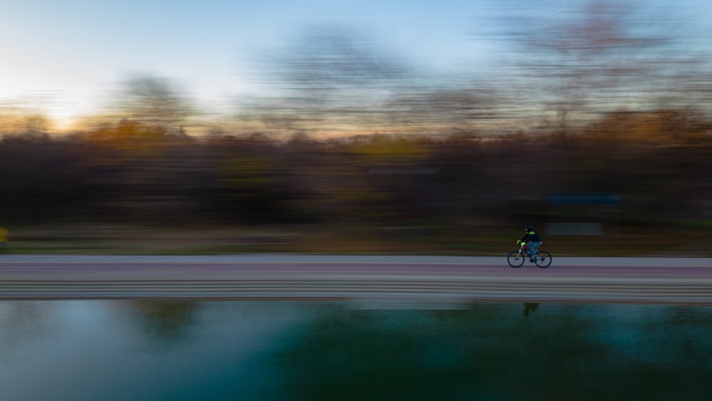 a person riding a bicycle on a road with trees in the background