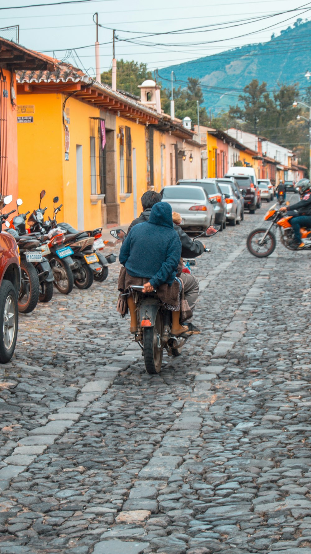 a person riding a motorcycle down a cobblestone street