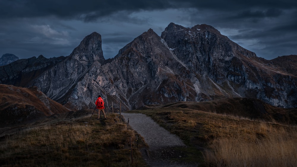 a person walking on a trail in front of a mountain