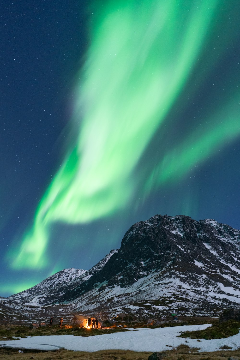 a green aurora over a snowy mountain