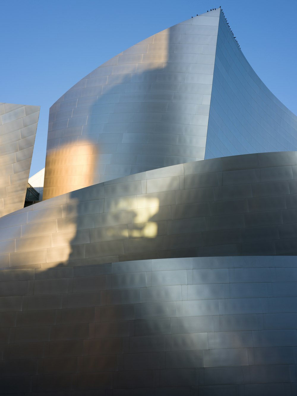 a large pyramid with a blue sky with Walt Disney Concert Hall in the background