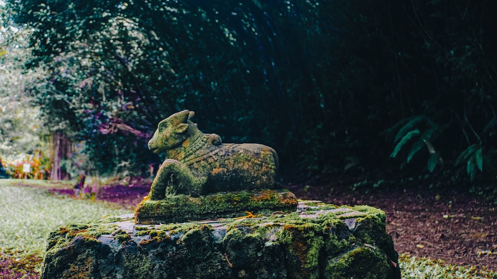 a statue of a lion on a rock in a park