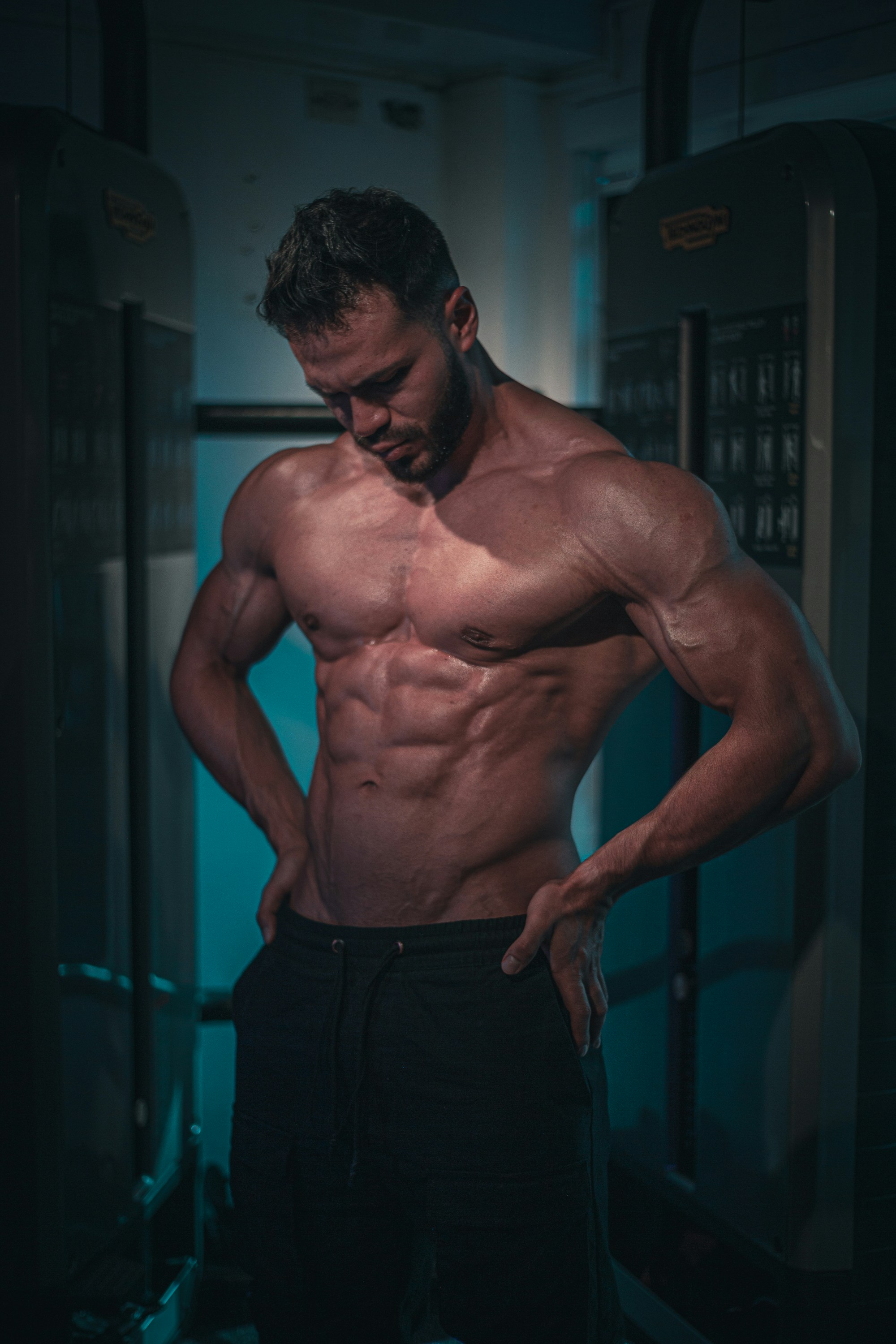Harpreet Singh fitness trainer — muscular athlete in gym attire, dark gym background with dramatic low-key lighting