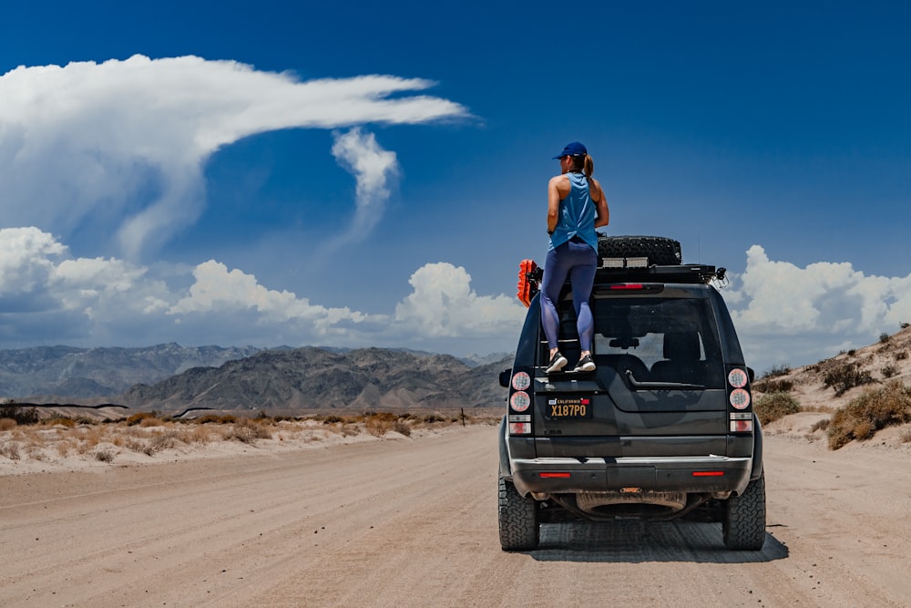 a man standing on the back of a truck on a dirt road
