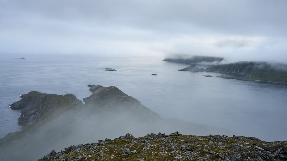 a rocky beach with a body of water in the background