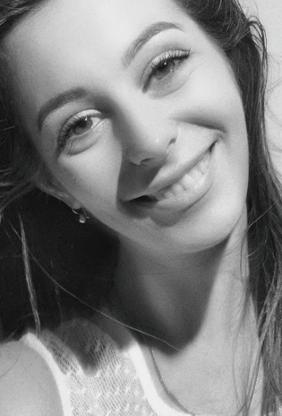 A close-up portrait of a young woman smiling softly in a studio setting.