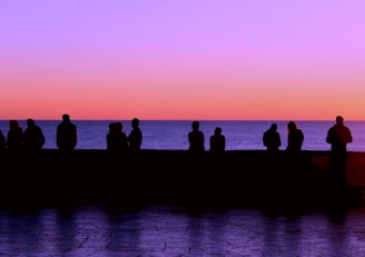 a group of people sitting on a dock at sunset