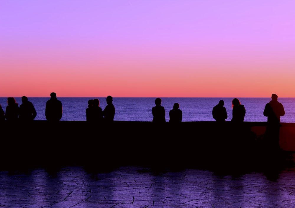 a group of people sitting on a dock at sunset