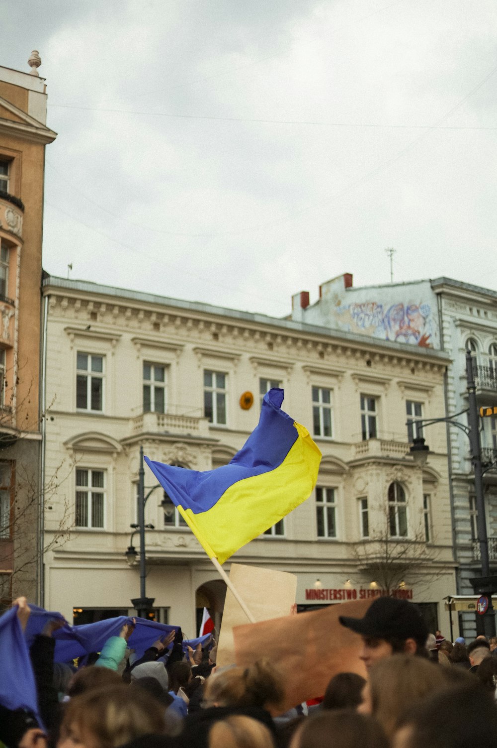 a crowd of people in front of a building with a blue flag