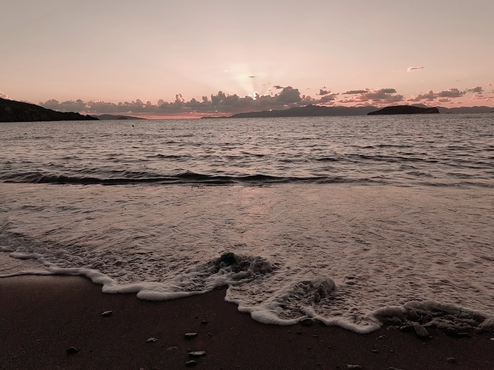 a beach with waves and a sunset