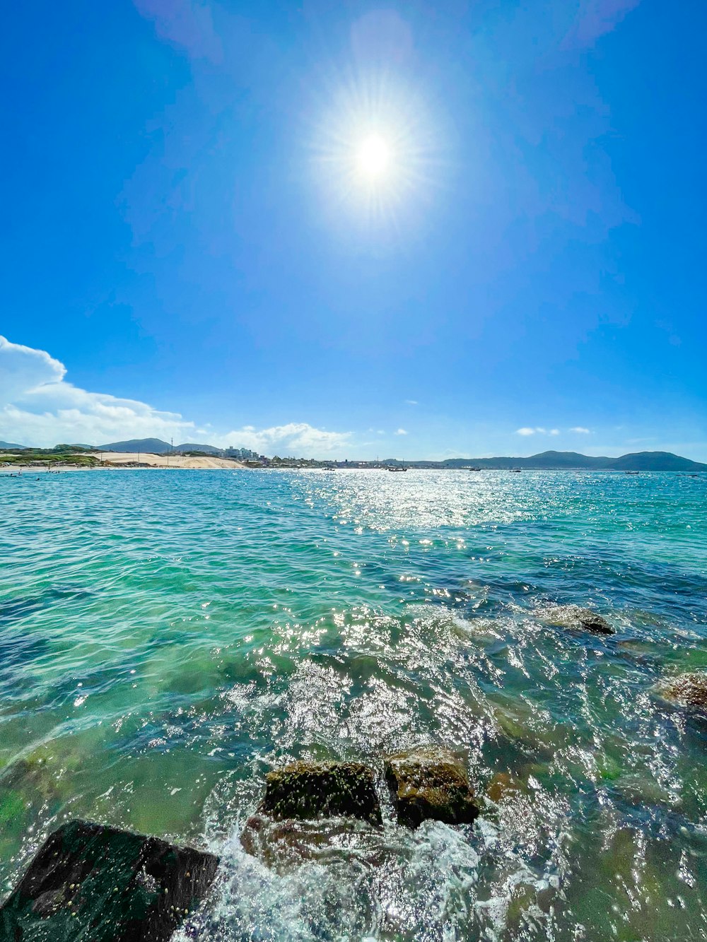 a body of water with rocks and a sunny day