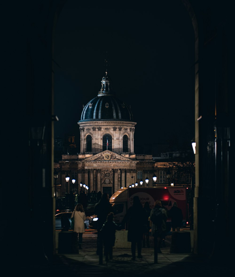 a group of people walking in front of a building at night