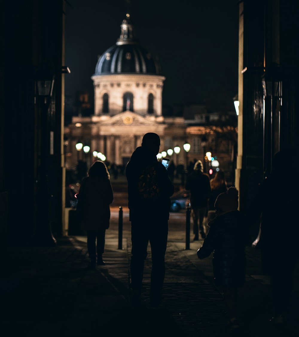 a group of people walking in front of a building at night