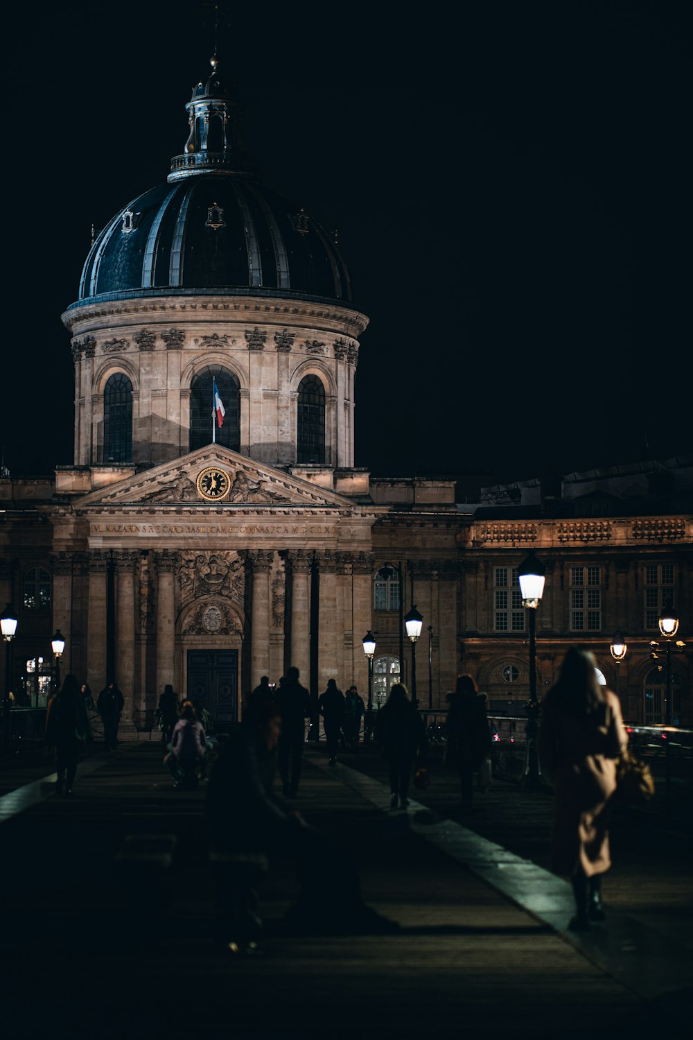 a large building with a dome and many people walking around