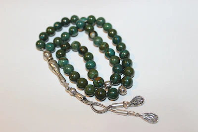 A collection of elegant prayer beads made from rare stones laid out on a velvet cloth highlighting their polished finish.