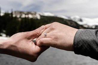 Close-up of hands shaking over a financial agreement with mountain views in the background.