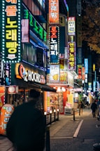 A vibrant city street at night glowing with neon signs reflecting urban energy.