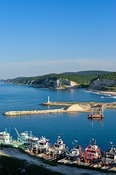 A coastal beach scene with fishing boats docked near the shore.