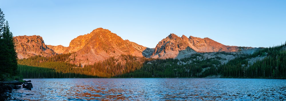 a body of water with trees and mountains in the background