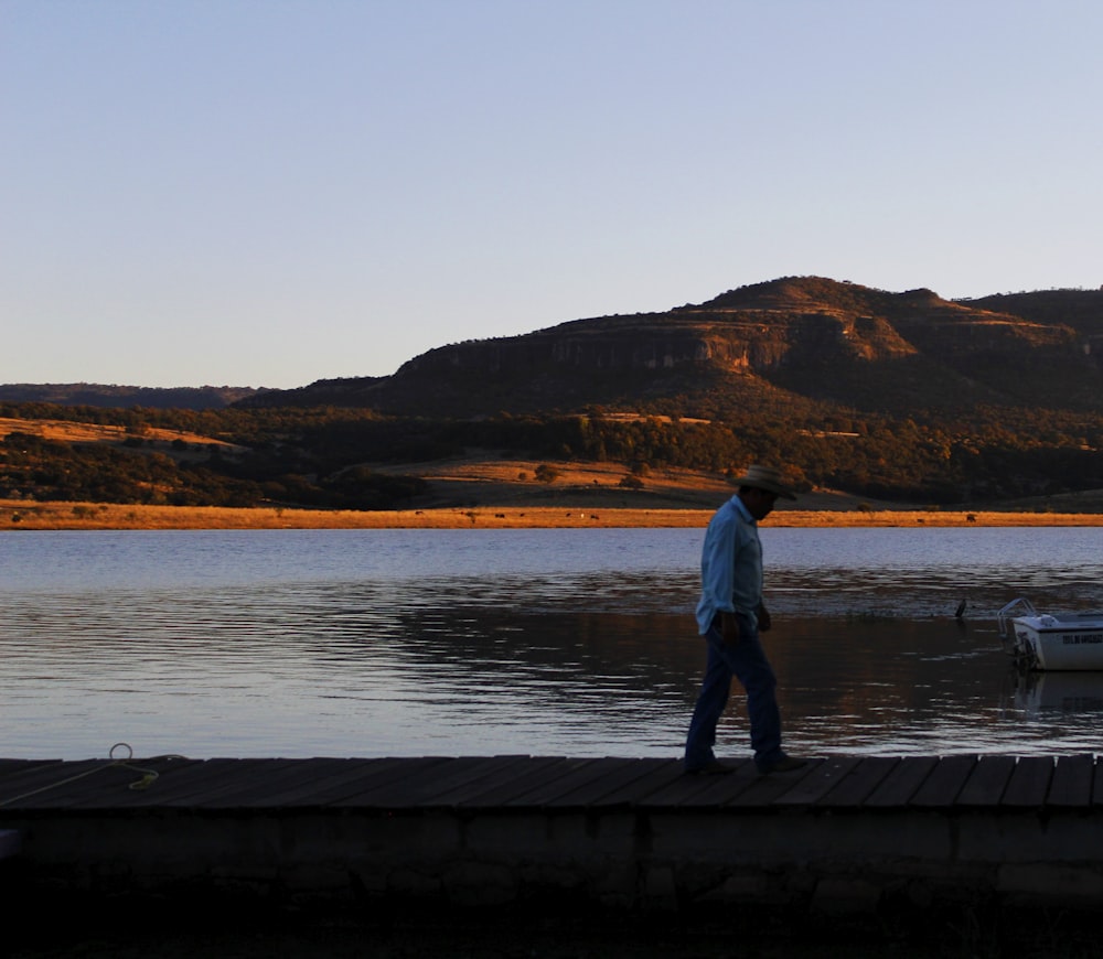 a man standing on a dock looking at a body of water