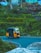 An auto rickshaw is navigating a curved road surrounded by lush greenery. The bright yellow vehicle contrasts against the dense vegetation and the clear blue sky above. The scene depicts a rural or suburban setting with a hint of infrastructure visible in the background.