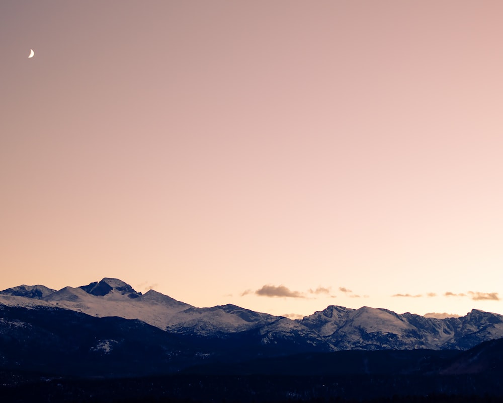 a mountain range with the moon in the sky