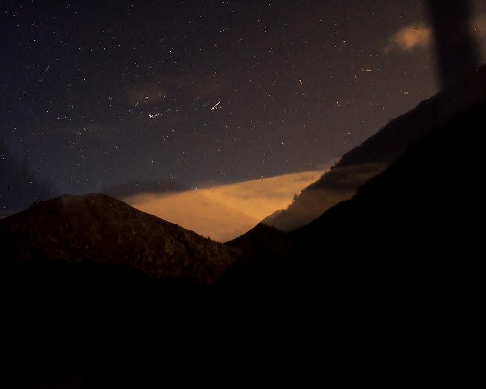 a view of the night sky with stars and a mountain