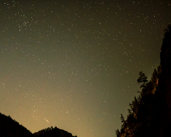 A serene view of the Aravalli hills with a luxury camp set against a starry night sky.