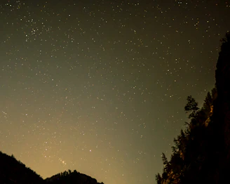 A serene view of the Aravalli hills with a luxury camp set against a starry night sky.